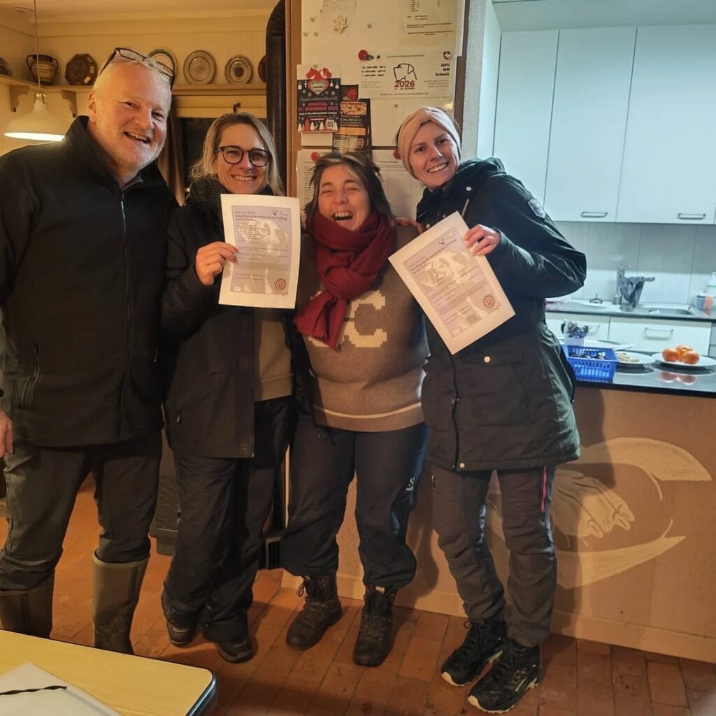 Gruppe von vier Menschen mit Zertifikaten in der Küche, lächelnd und stolz.